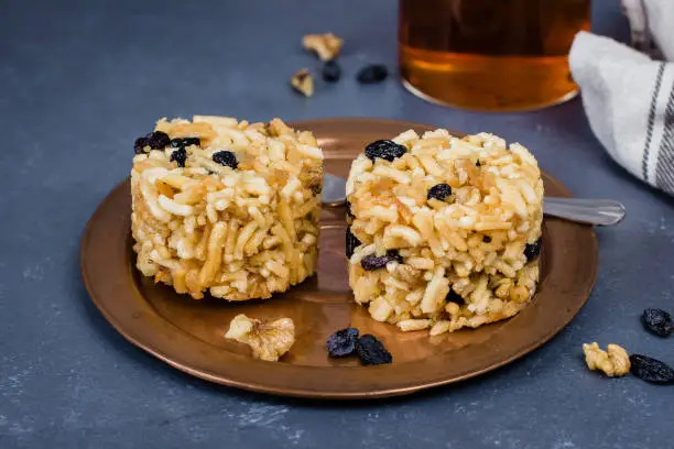 Photo of Eastern or Asian sweets (chak-chak) with honey, raisins and walnut on stone concrete table background