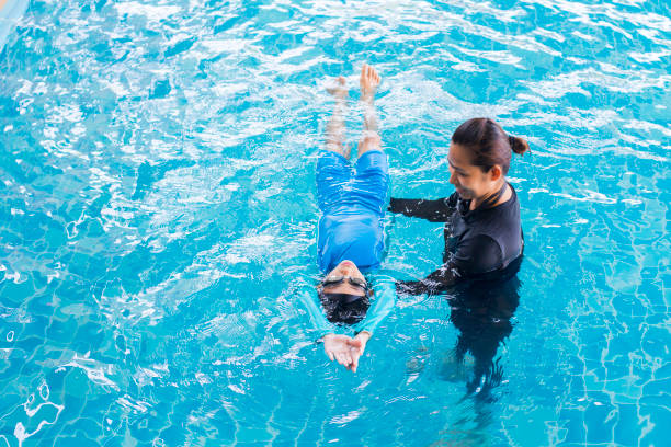 mädchen mit coach bei dem freizeitzentrum schwimmen lernen - schwimmen stock-fotos und bilder