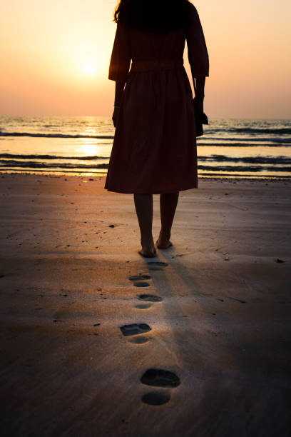 istock Girl walking on the beach at sunset 935935580