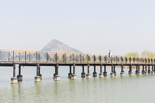 perspective view of young woman walking on bridge at a spring afternoon,china.