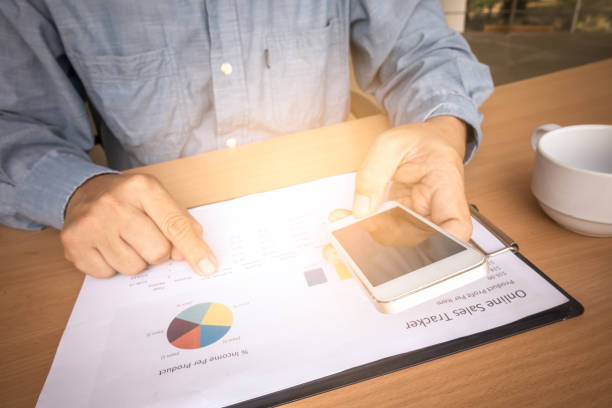 istock Business man analyzing investment charts with smart phone and calculator on office desk table.Close up.Financial Report Revenue Statistical Accounting Concept. 935937814