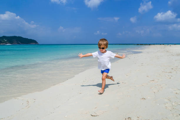istock Playful boy having fun while running on the beach with his arms outstretched. 935948368