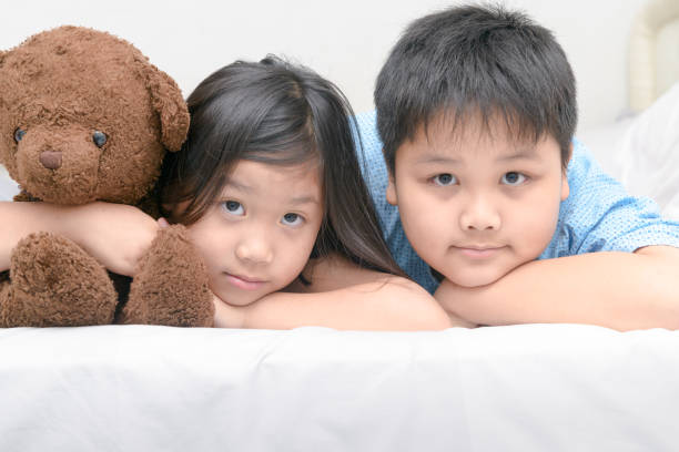 istock sister and brother lying on bed 935948546