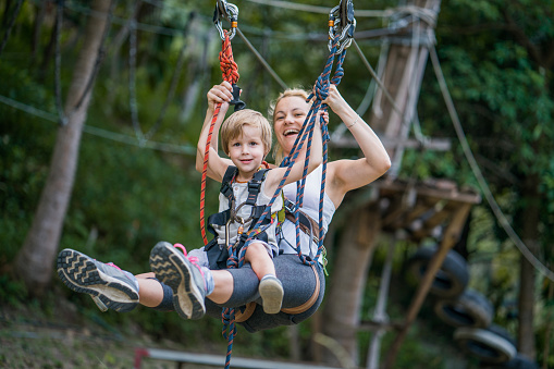Carefree mother and son having fun on canopy tour in nature. Focus is on boy.