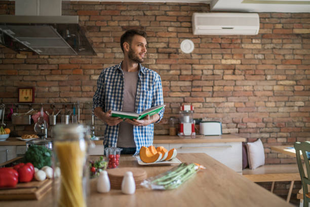 istock Smiling man following recipe from a cookbook in the kitchen. 935951516