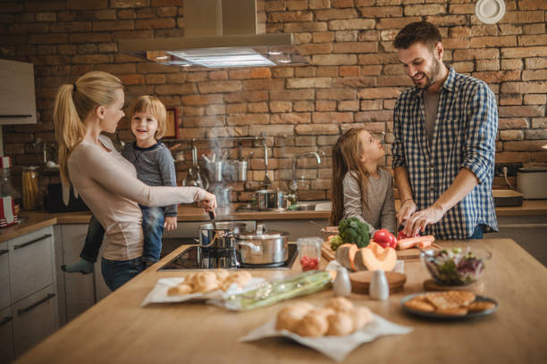 istock Young smiling parents enjoying while preparing lunch with their kids in the kitchen. 935955128