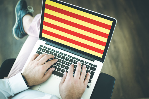 People using laptop and showing on the screen the flag of CATALONIA
