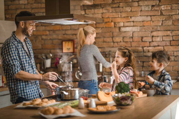 istock Happy family cooperating while making lunch in the kitchen. 935955488