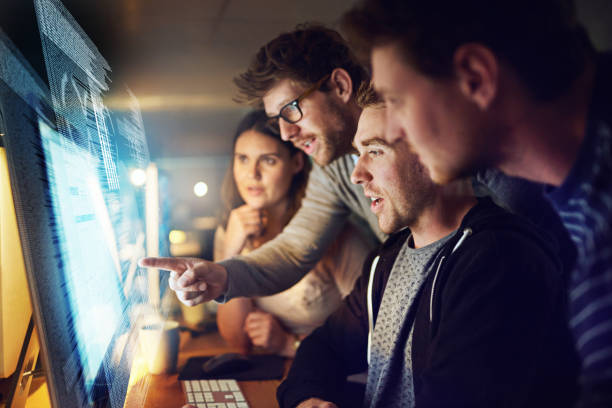 Adding modifications to their latest code Shot of a group of programmers working on a computer code at night dedicated team stock pictures, royalty-free photos & images