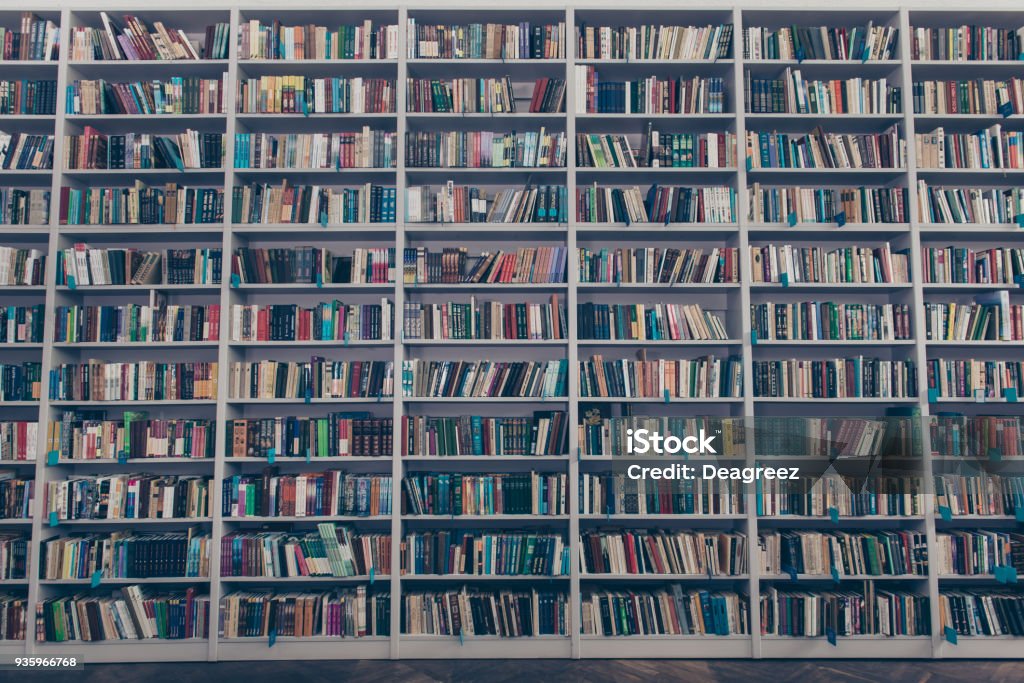 Ancient library interior design with massive wooden grey book shelves, full of colorful literature, tomes, publications, and wooden floor Large Stock Photo