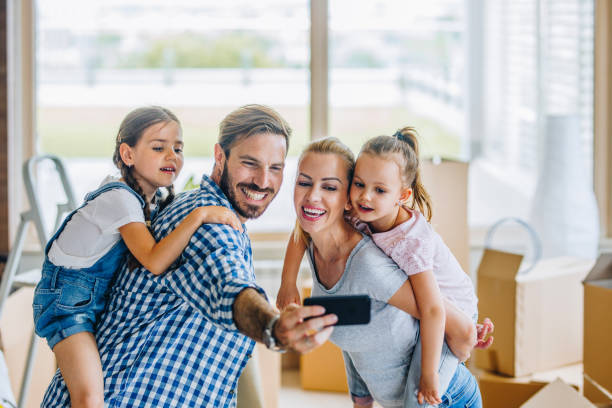 istock Young smiling family taking a selfie with smart phone while moving into a new home. 935967044