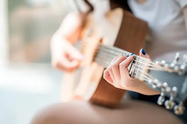 woman hands playing acoustic guitar, close up view, shallow DOF