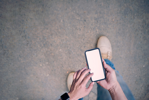 man on walking and holding smartphone with white blank screen,top view of man holding smartphone,