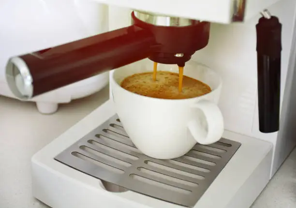 an espresso coffee machine is making and pouring fresh coffee into white cup
