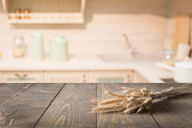 istock Blurred and abstract kitchen background. Wooden tabletop with wheat and defocused modern kitchen for display your products. 935971384