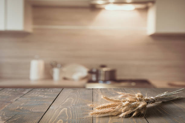 istock Blurred and abstract kitchen background. Wooden tabletop with wheat and defocused modern kitchen for display your products. 935971388