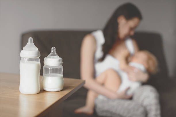 botellas con leche en el fondo de madre sosteniendo en sus manos y su bebé de la lactancia materna. cuidado de bebés y maternidad. - human nipple fotos fotografías e imágenes de stock