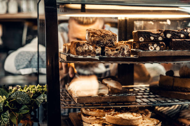 A man holds chocolate cake at the counter in the bakery shop.