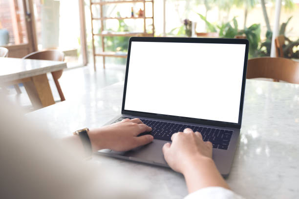 istock Mockup image of hand using and typing on laptop with blank white desktop screen on table in modern cafe 935978724