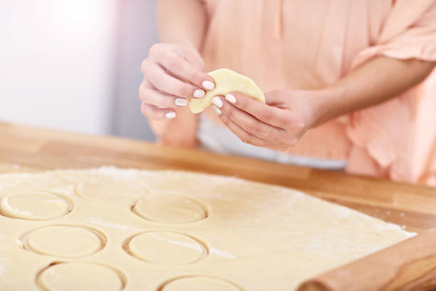 Portrait of young woman trying to make pierogi in kitchen