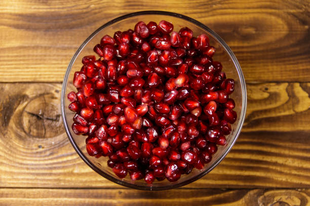 istock Pomegranate seeds in glass bowl on wooden table 935978896