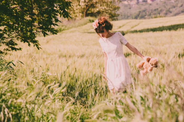 istock Beautiful woman keeping teddy bear in the spring fields 935979180