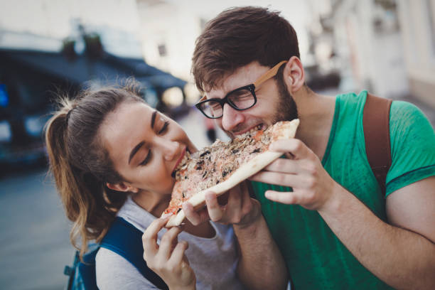 feliz pareja compartir pizza en la calle - people traveling friendship backpack expressing positivity fotografías e imágenes de stock