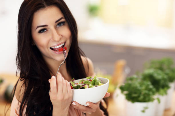 istock Happy woman preparing salad in modern kitchen 935983698