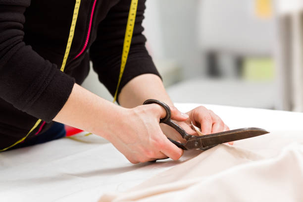 istock Dressmaker cutting fabric with scissors 935983826
