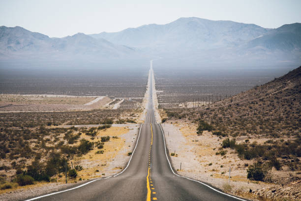 Classic panorama view of an endless straight road running through the barren scenery of the American Southwest with extreme heat haze on a beautiful sunny day with blue sky in summer