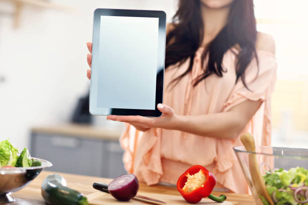 istock Happy woman preparing salad in modern kitchen and holding tablet 935986228