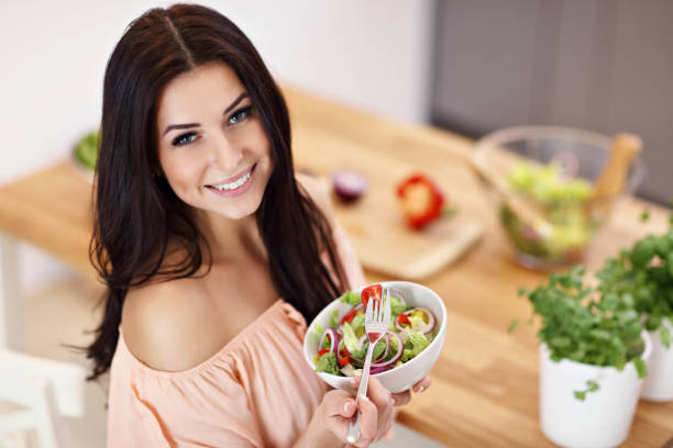 istock Happy woman preparing salad in modern kitchen 935986324
