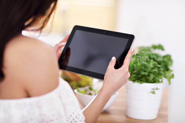 istock Happy woman preparing salad in modern kitchen and holding tablet 935986546