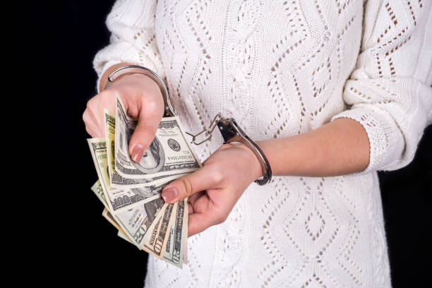 istock woman holding dollar bills in handcuffs 935989466