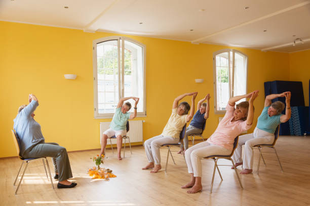 istock active senior women in yoga class exercisig on chairs, 935990630