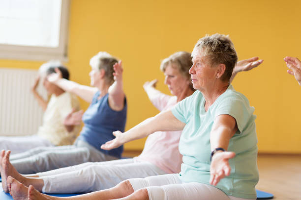 istock Active senior women in yoga class exercising on mat sitting 935993464