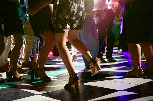 People Dancing on a block shaped dance floor at night outdoors with the focus on a girl dancing with high heals bottom half lifting the one leg Cape Town South Africa