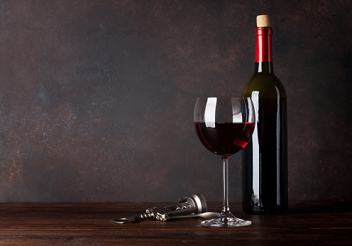 Red wine bottle and glass in front of blackboard wall. With copy space for your text