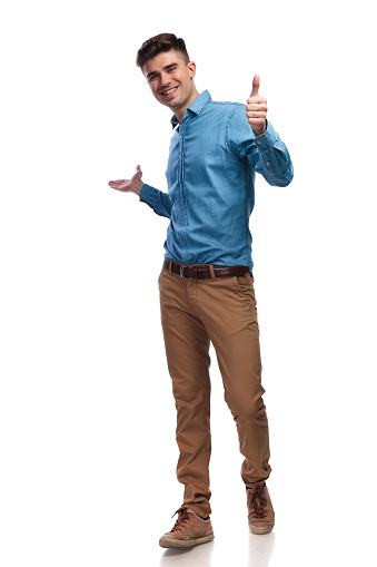 laughing young casual man presenting and making ok sign on white background