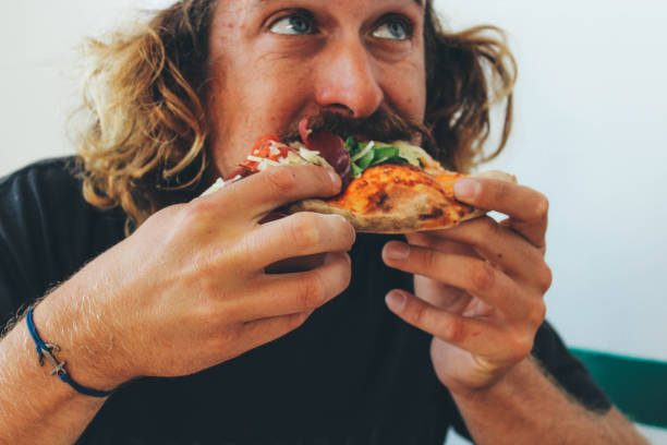 uomo che mangia pizza in un ristorante - man eating foto e immagini stock