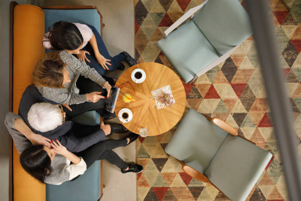 coppia anziana, nonna e nonno con i suoi nipoti seduti in un hotel retrò bevono caffè e chiacchierano. anziani attivi. direttamente sopra. vista aerea della famiglia nel caffè. - couple blond hair social gathering women foto e immagini stock