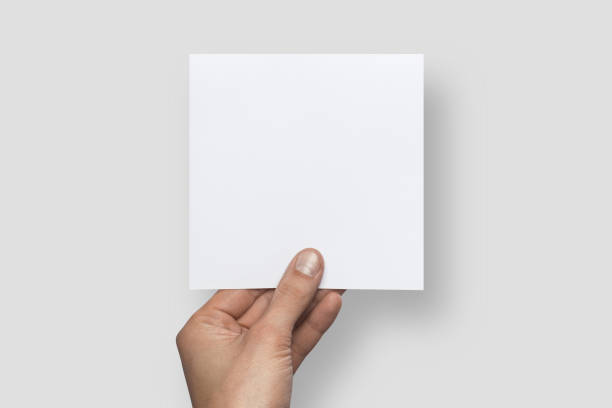 istock Mockup square empty blank white postcard holds the man in his hand. Isolated on a gray background 936004572