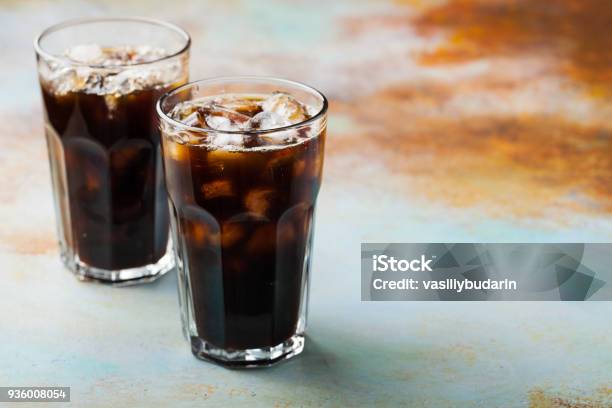 Ice Coffee In A Tall Glass With Cream Poured Over And Coffee Beans Cold Summer Drink On A Blue Rusty Background With Copy Space Stock Photo - Download Image Now