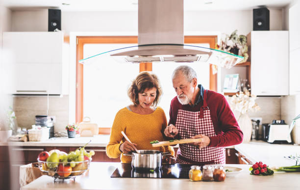 senior couple preparing food in the kitchen. - cooking senior adult healthy lifestyle couple imagens e fotografias de stock