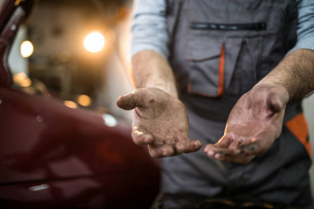 Senior mechanic working at car service showing dirty hands