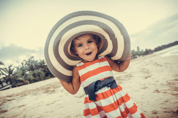 Pretty little girl in  striped dress and straw hat enjoying sea