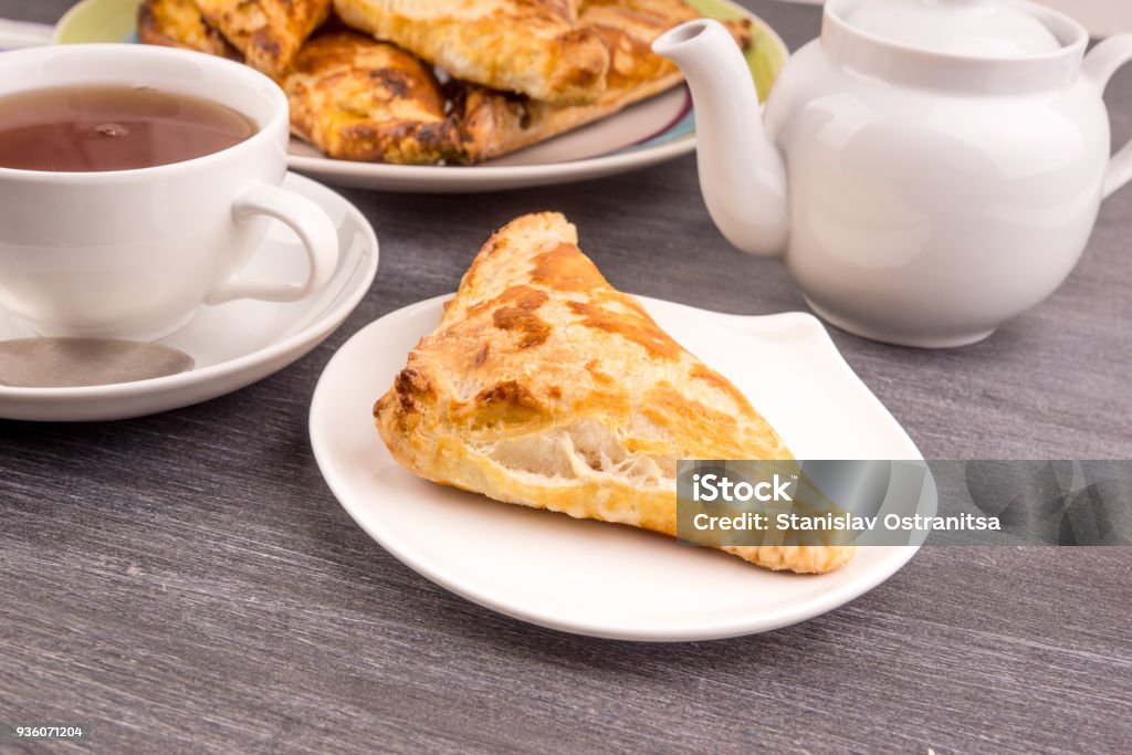 Delicious golden triangles of puff pastry on the table and a cup of tea - top view Appetizer Stock Photo