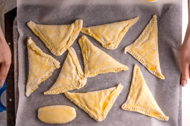 istock woman holds a baking sheet with triangles of puff pastry 936078302