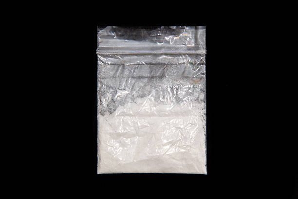 Plastic bag of white powdered mephedrone on black background