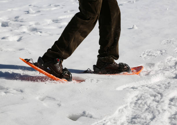 istock man walks with orange snowshoes 936087216